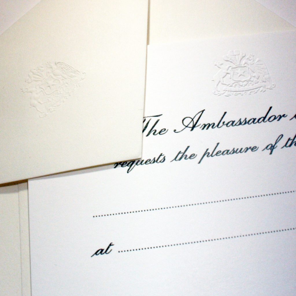 Diplomatic blind embossed crest on invitations and envelopes.